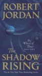 The Shadow Rising paperback, December 2019 mass-market edition from Tor Books. The cover has the snake-wheel symbol on a dark blue background.