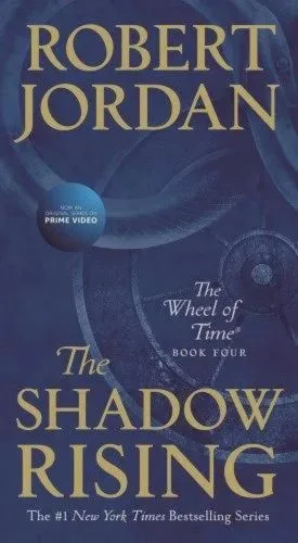 The Shadow Rising paperback, December 2019 mass-market edition from Tor Books. The cover has the snake-wheel symbol on a dark blue background.