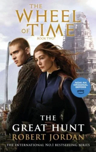 The Great Hunt paperback, Orbit's August 2023 media tie-in edition. The cover has head and shoulder images of Josha Stradowski’s Rand and Rosamund Pike's Moiraine, with the White Tower behind them.