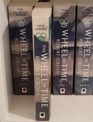The Wheel of Time books on a shelf with New Spring pulled forwards, signifying its position if you read New Spring after The Eye of the World.