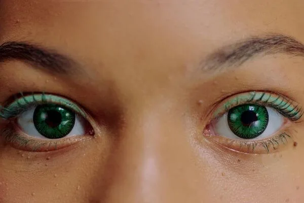 Close-up of a woman with green contact lenses staring straight ahead.
