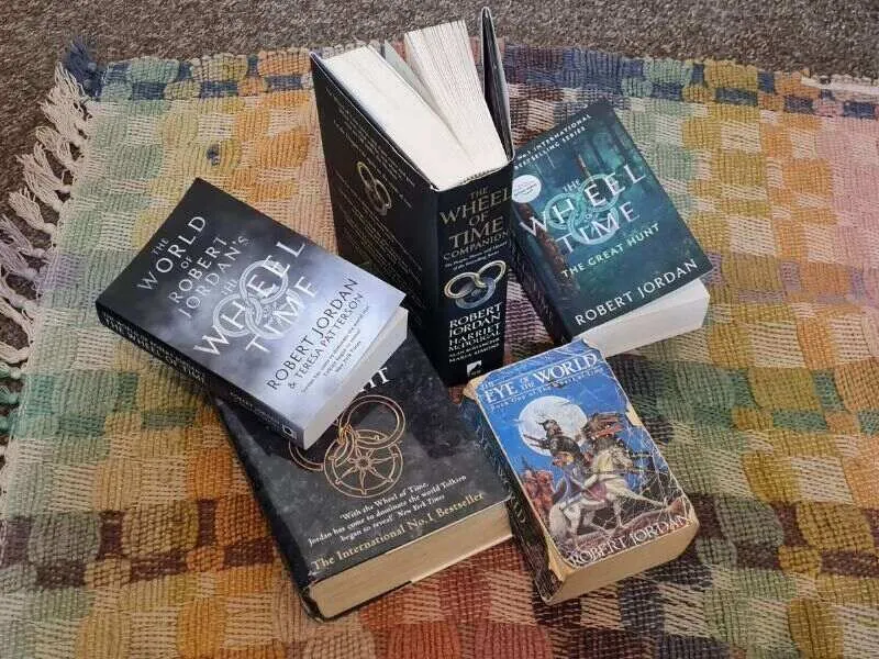 A variety of Wheel of Time books on a patchwork rug.